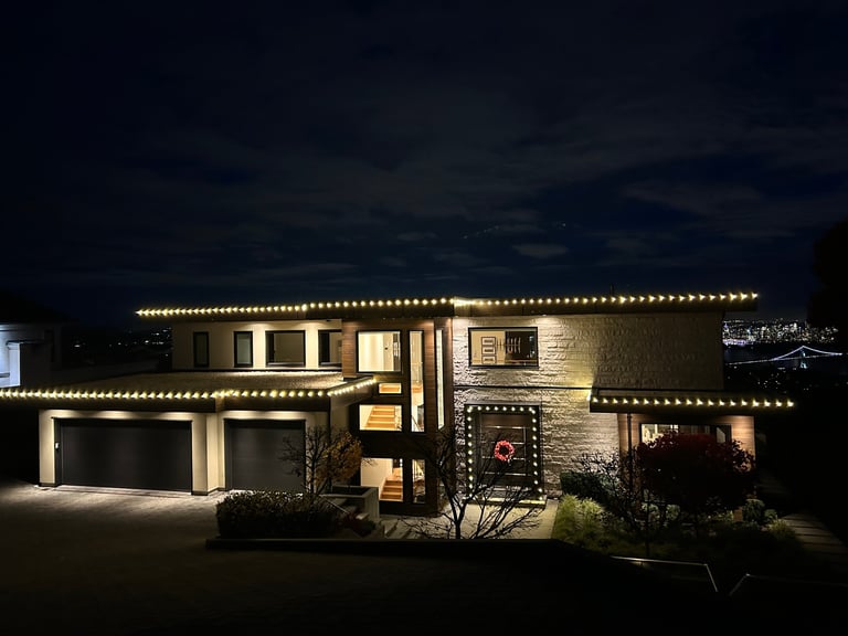 Modern house exterior at night with warm lighting, double garage, stone and brick facade, and landscaping